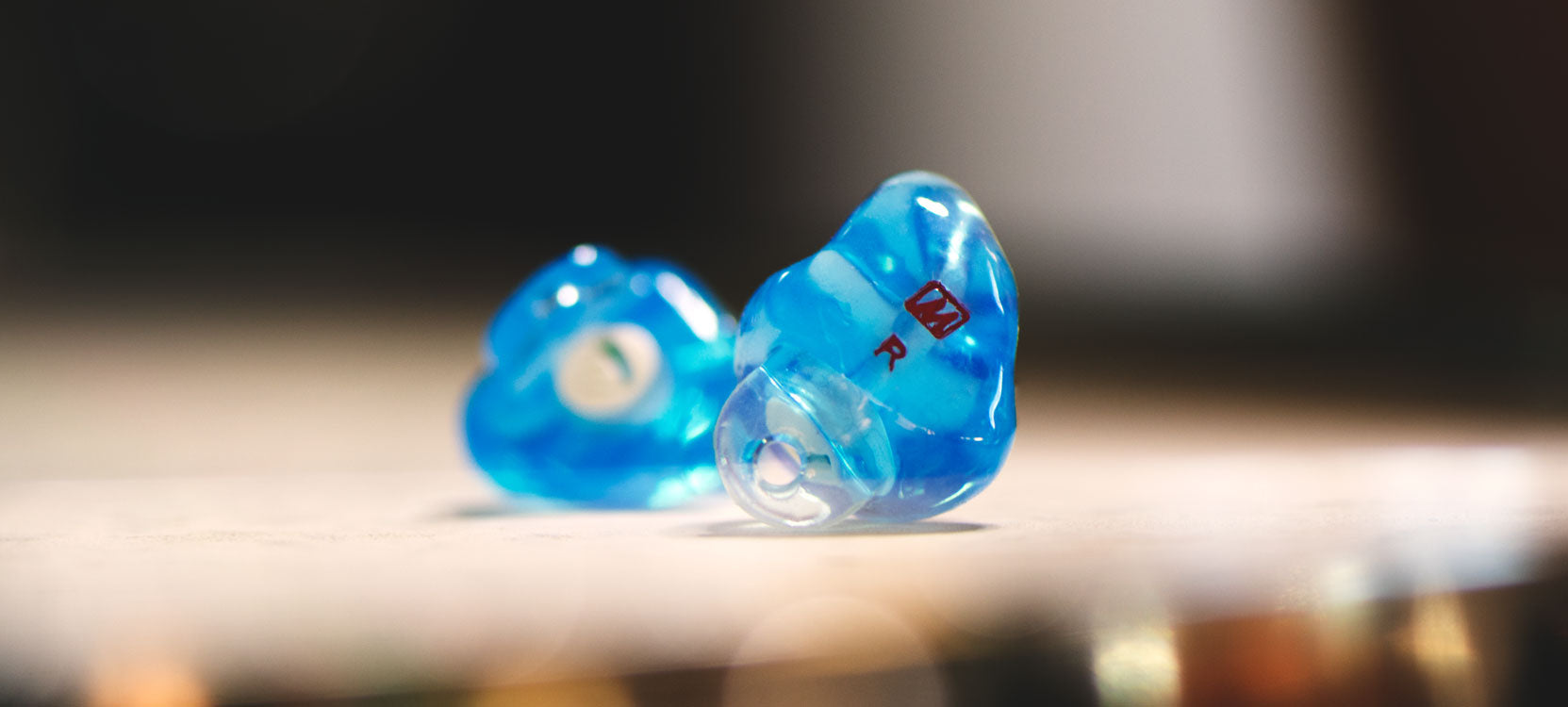 Blue custom ear plugs with a caption that reads Isolation Tailored for You